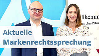 zwei Herren vor Schriftzug 